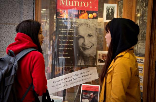 Duas jovens em frente a vitrine com foto de Alice Munro